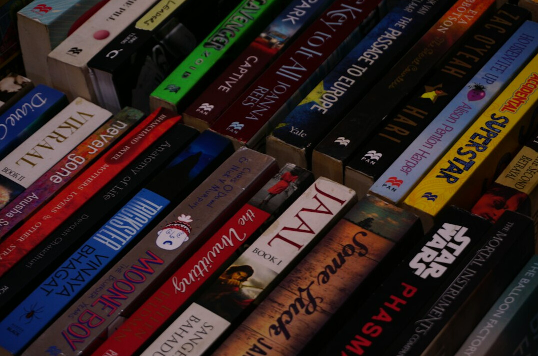 Stack of paperback mystery books with a pocket magnifier